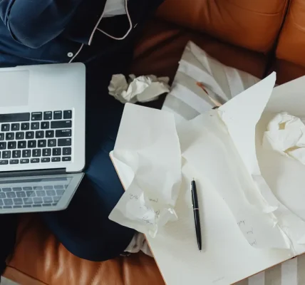 laptop beside crumpled draft papers on a table
