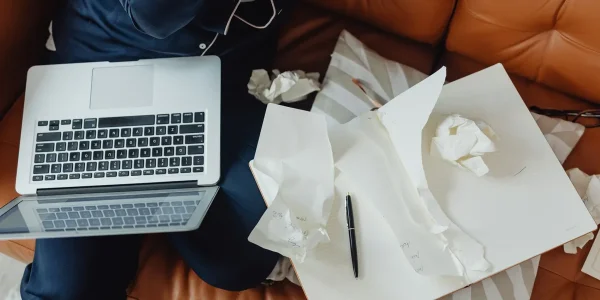 laptop beside crumpled draft papers on a table