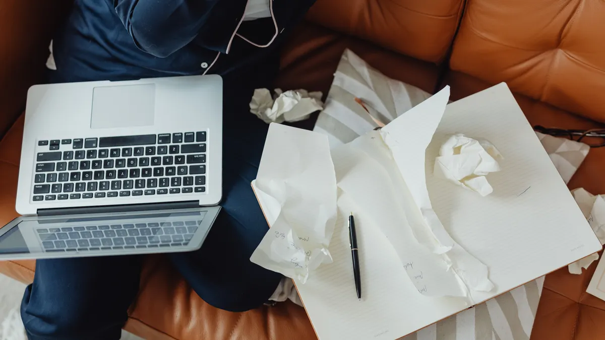 laptop beside crumpled draft papers on a table